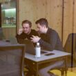 two men sitting at a table with a laptop